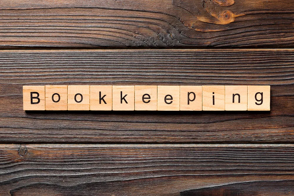 Wooden blocks spelling "Bookkeeping" on a wooden surface, symbolizing accounting and financial reporting services