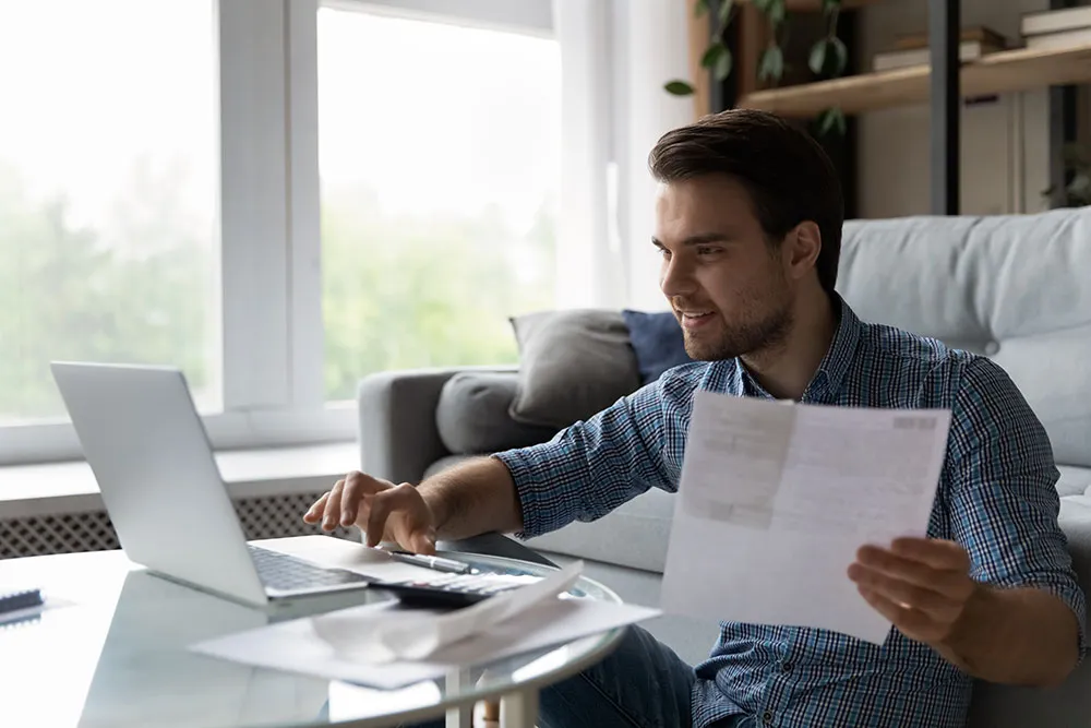 Man working on his laptop with financial documents, managing accounts and bookkeeping services in a home office setting in Dubai