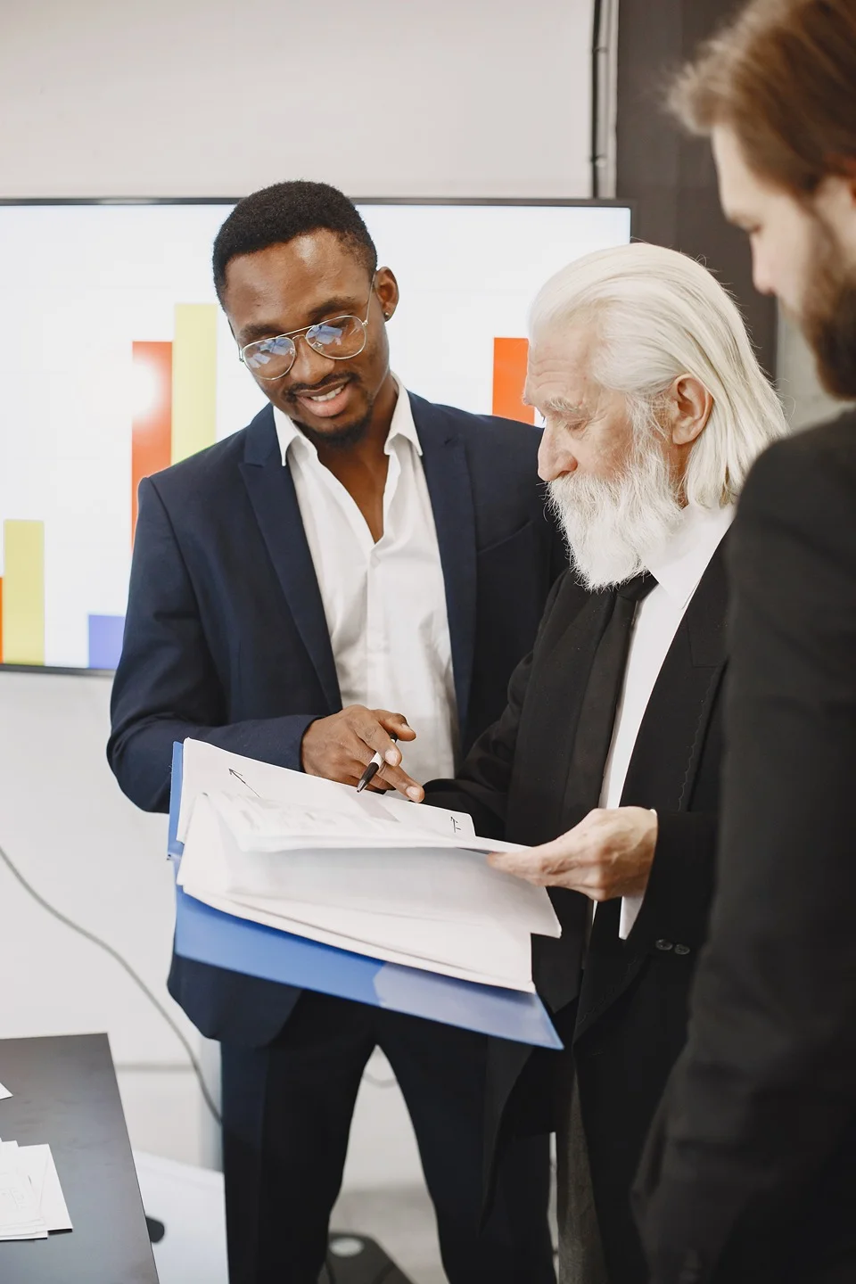 African businessman in a black suit discussing with international partners