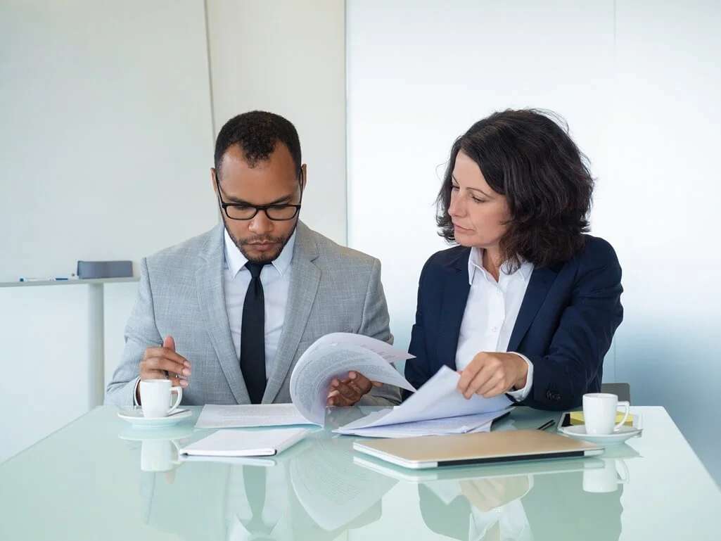 Business colleagues reviewing and checking agreement texts in a meeting.