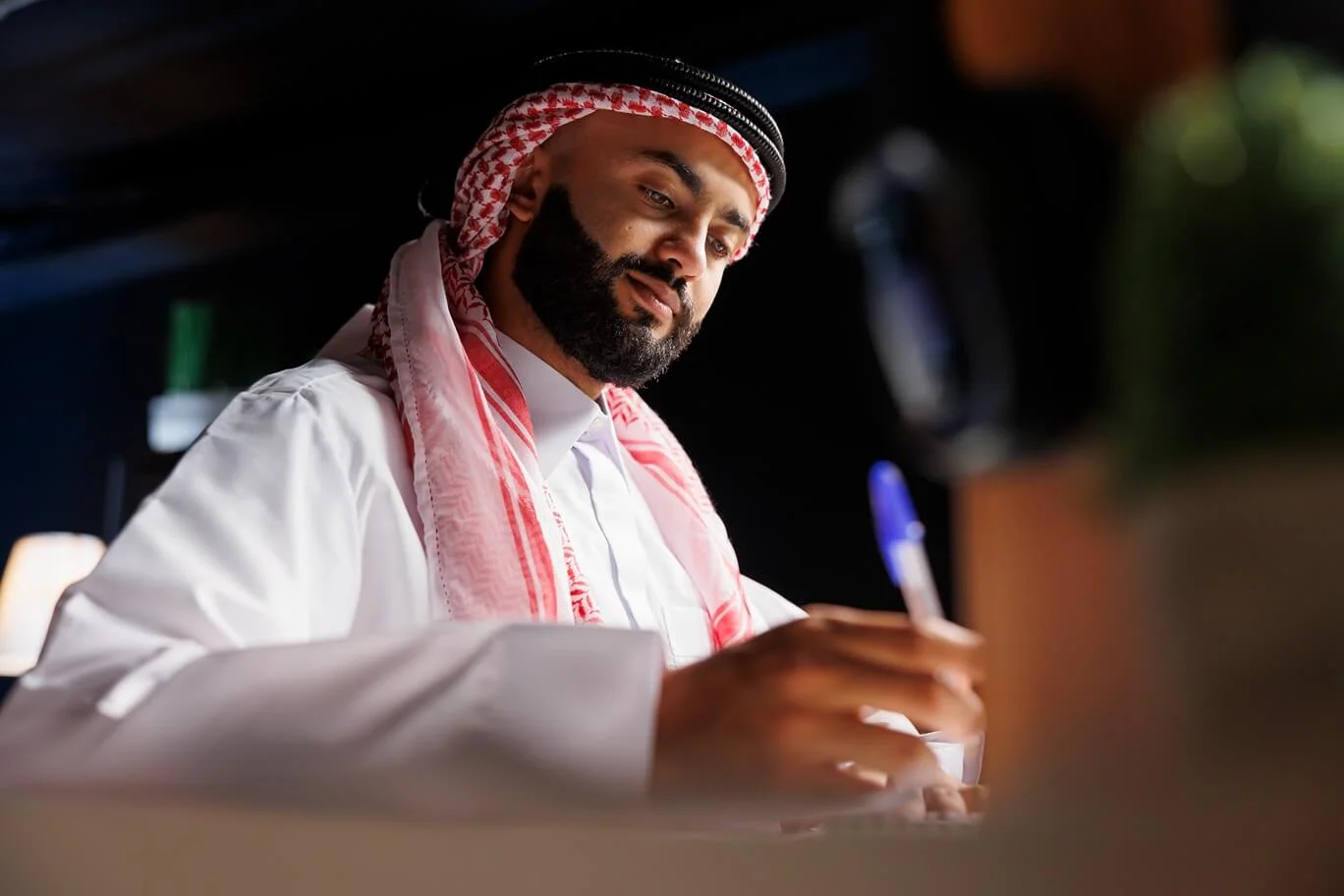 Arab man signing documents for offshore account opening in Dubai.